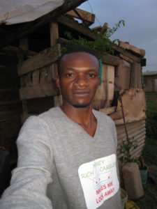Shimba taking a selfie outdoors in front of a slum