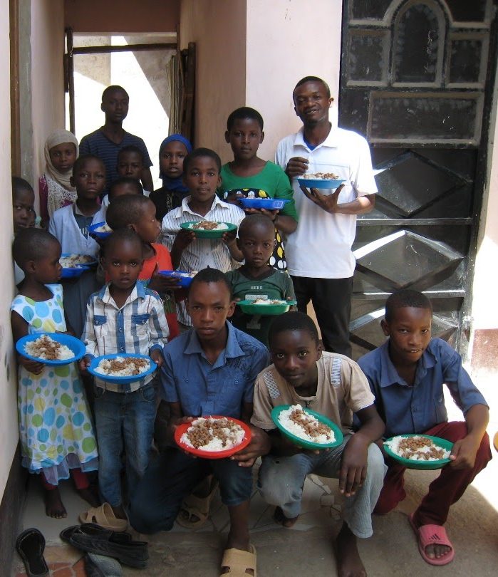 A group of children holding plates of beans and rice
