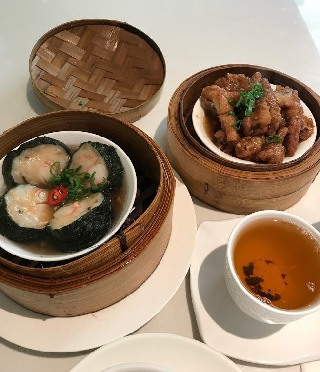 Two bowls full of dim sum and a cup of black tea
