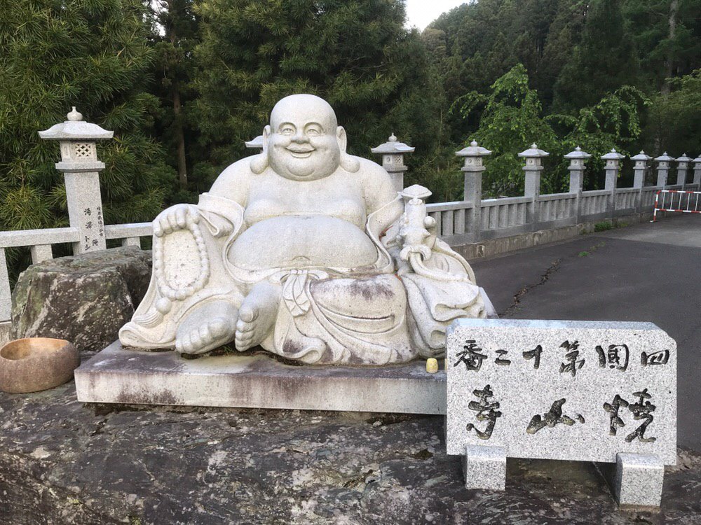 White stone buddha in front of a forest