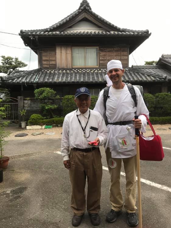 Sergiu Kondanna and Japanese man stand side by side in front of a Japanese style house