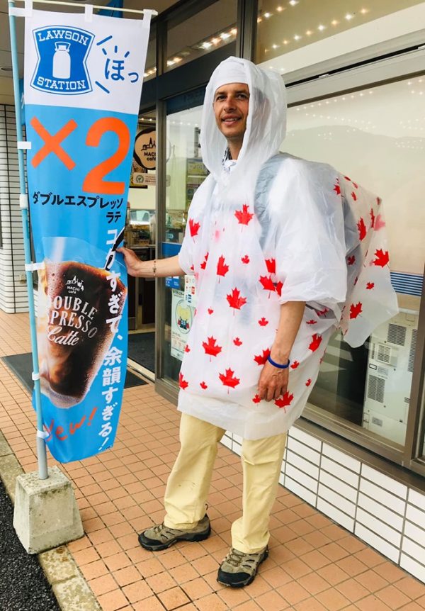 Sergiu Kondanna wearing a raincoat with Canadian maple leaves next to a Lawson sign